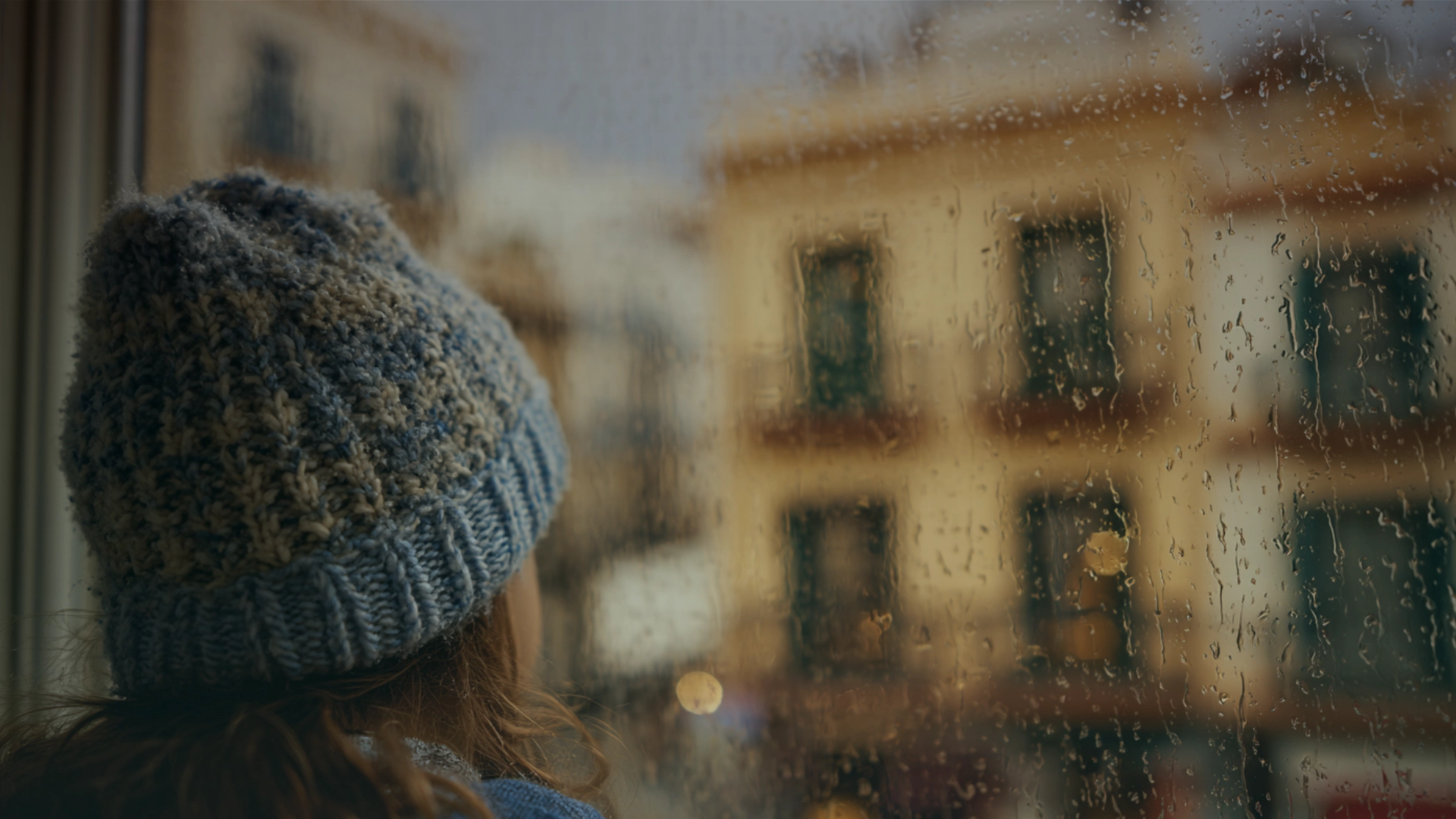 Hombre caminando solo bajo la lluvia en una calle empedrada de un pueblo español